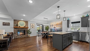 A modern kitchen with dark cabinets, a central island, and a fireplace.