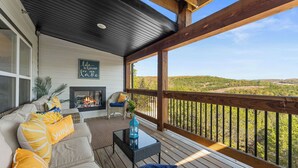 A covered porch with a sofa, a table, and a fire pit.