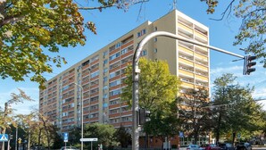 Un immeuble résidentiel à plusieurs étages, doté de balcons, d’un passage piéton et d’un feu de signalisation.