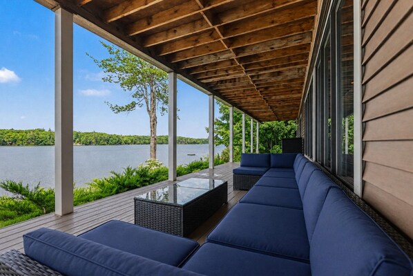 A covered outdoor seating area with a view of a lake.
