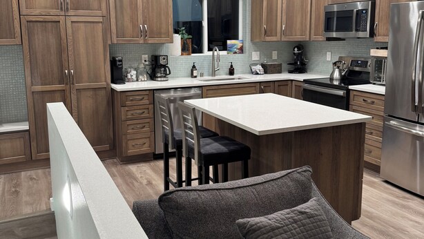 A modern kitchen with wooden cabinets, stainless steel appliances, and a central island with seating. - City Retreat, 2 bdrm near Airport (Anchorage)