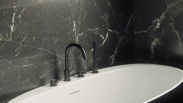 A modern bathroom with a freestanding bathtub, dark marble walls, and a sleek black faucet.