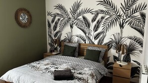 A bedroom with a bed, nightstands, a wall clock, and a wall-mounted lamp. - Quiet two-bedroom house on the banks of the Seine with parking space. Outdoor terrace (Cleon)