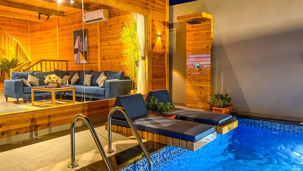 Een houten chalet met zwembad, een bank en een trap.