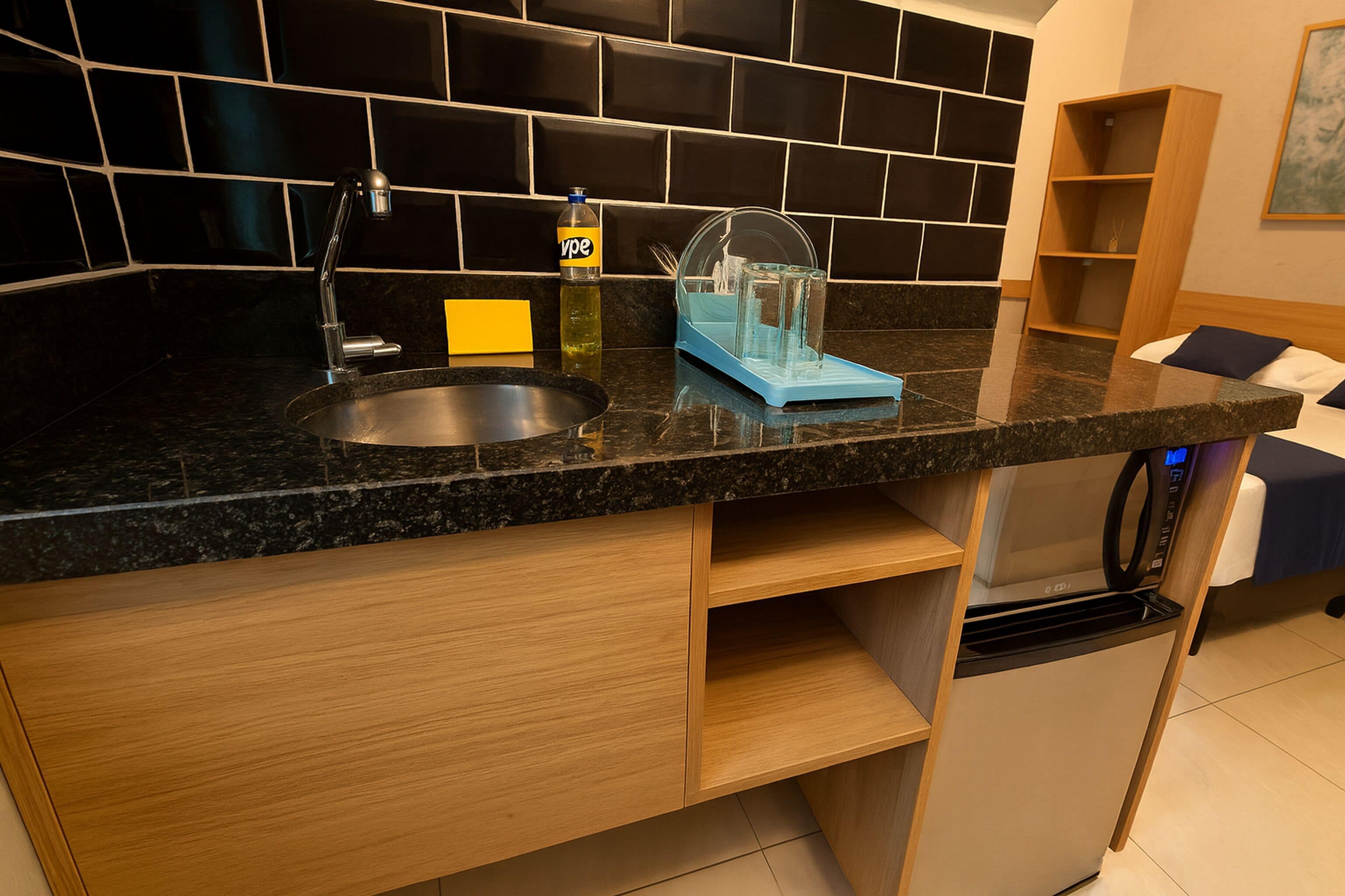 A modern kitchen with a granite countertop, a stainless steel sink, a built-in dishwasher, and a wooden cabinet.