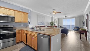 A modern kitchen with wooden cabinets, stainless steel appliances, and a granite countertop. - Emerald Isle Resort 2305 (Panama City Beach)