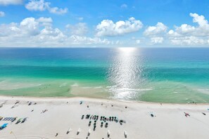 Une plage aux eaux turquoise et limpides, un rivage sablonneux et une rangée de parasols.