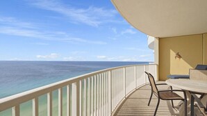 A balcony with a view of the ocean, a table, and two chairs. - Emerald Isle Resort 2305 (Panama City Beach)