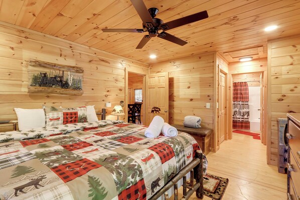 A wooden cabin bedroom with a bed, a ceiling fan, and a painting of bears. - Hot Tub & Fire Pit: Secluded Blue Ridge Cabin! (Blue Ridge)