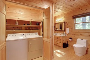 A compact wooden cabin with a laundry area, a sink, and a toilet. - Hot Tub & Fire Pit: Secluded Blue Ridge Cabin! (Blue Ridge)