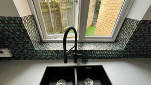 A kitchen with a black sink, a window above it, and a tiled backsplash.