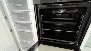 An open oven with a glass door, a white interior, and a tiled floor.
