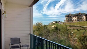 A balcony with a chair and a small table, overlooking a landscaped area with a building in the background. - 3Bed/2bath Deluxe unit in the Breathtaking Smoky Mountains!  (Sevierville)