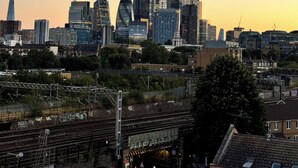 A city skyline with modern buildings, a railway track, and a bridge. - The Charm London  (Londres)