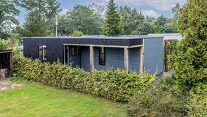 A modern, single-story house with a dark exterior, a covered porch, and a well-maintained garden. - Modern Chalet in the Veluwe (Putten)