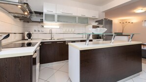 A modern kitchen with a central island, white cabinetry, and stainless steel appliances.