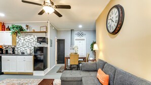 Ein Wohnzimmer mit einem grauen Ecksofa, einem Couchtisch und einer Wanduhr.