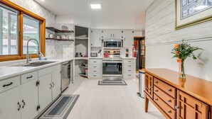 Een moderne keuken met witte kastjes, een houten aanrechtblad en een ingebouwde oven.