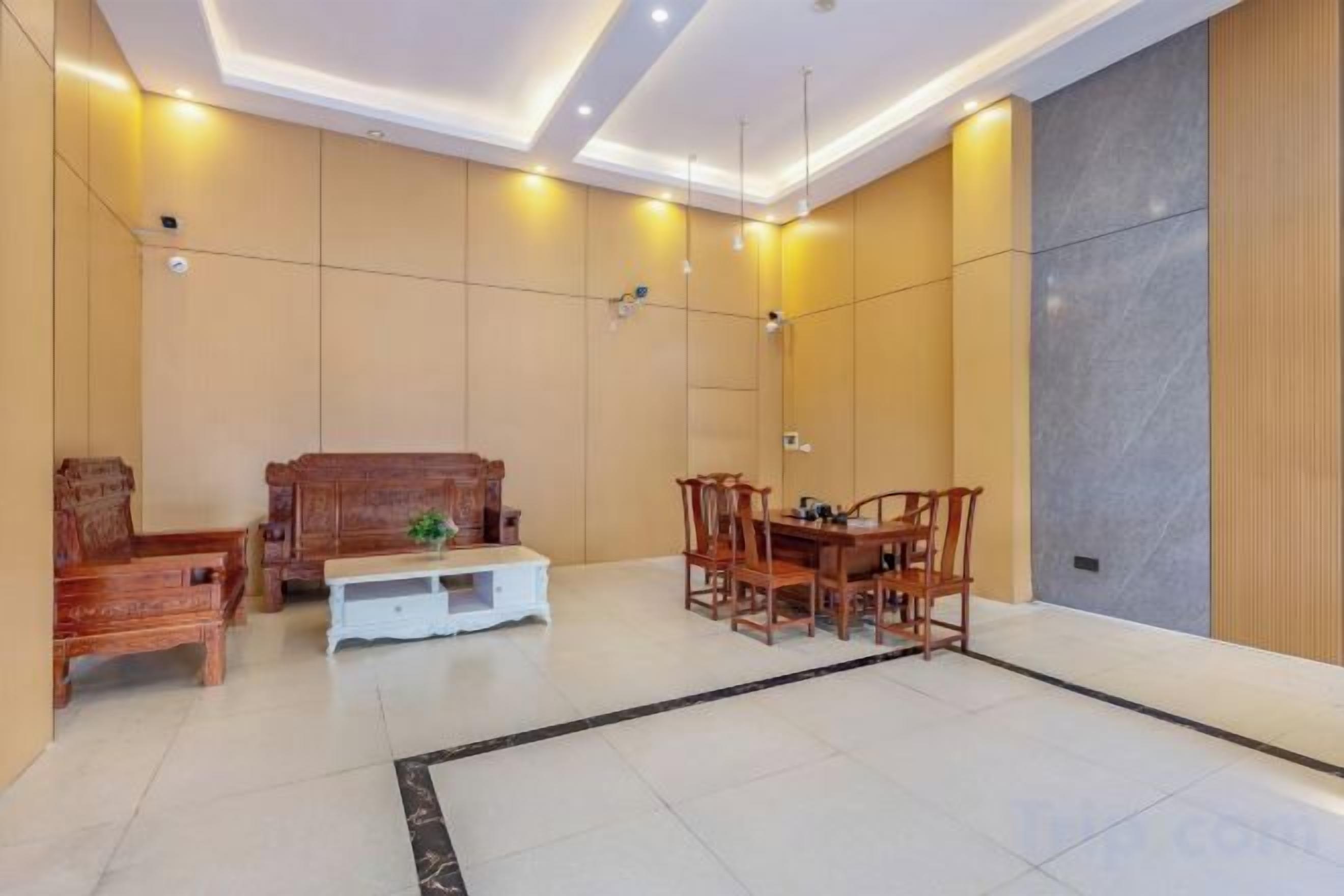 A hotel lobby with a seating area, a dining table, and a large mirror on the wall.