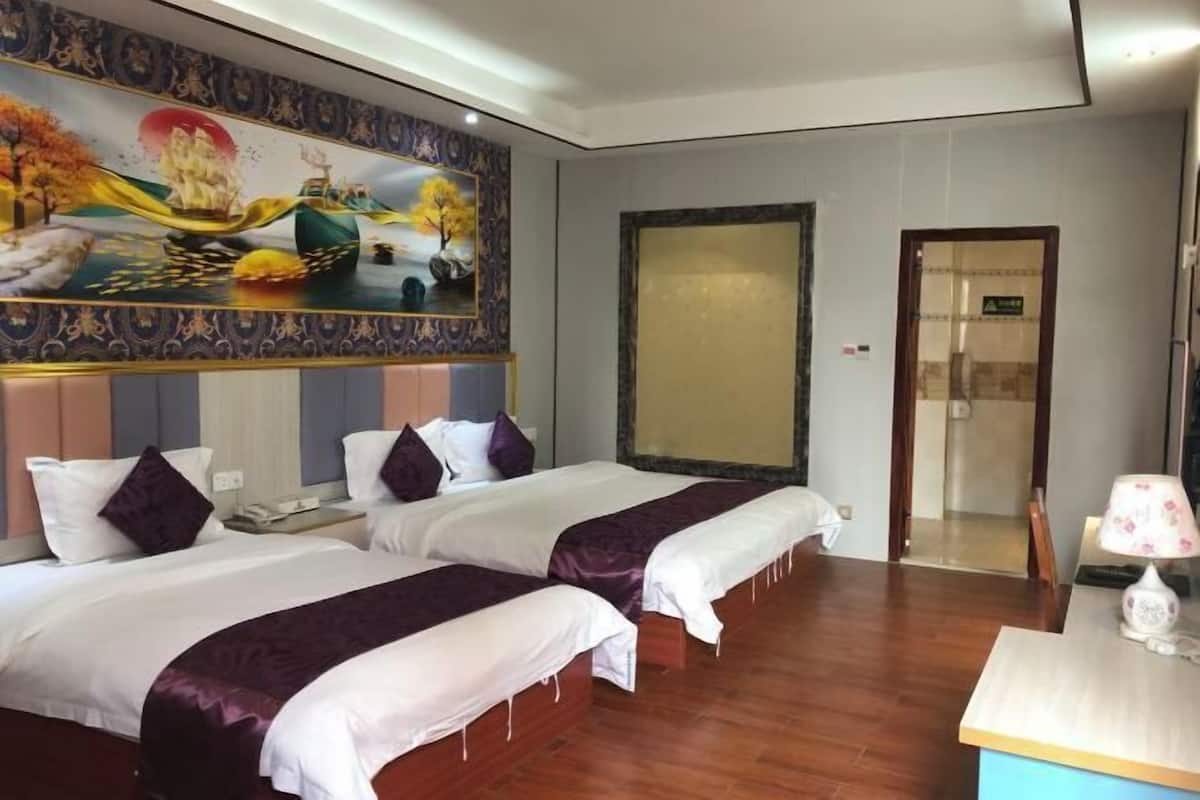 Habitación de hotel con dos camas, un mural grande en la pared, suelo de madera y un escritorio con lámpara.