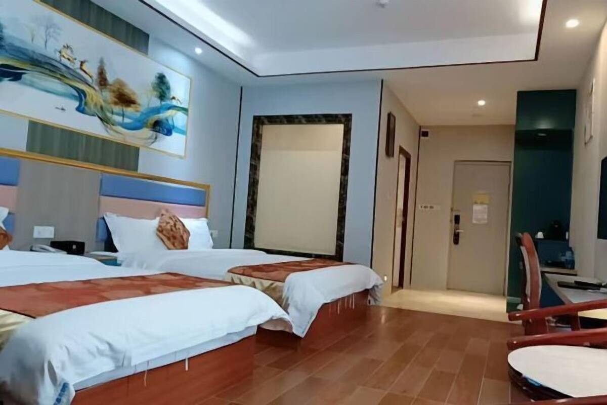 Una habitación de hotel con dos camas, un cuadro en la pared, un escritorio y una silla.