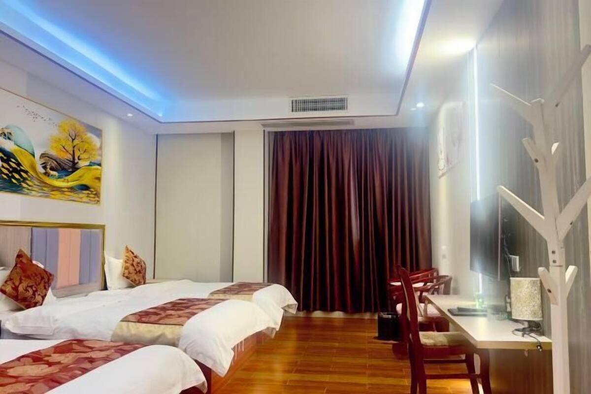Una habitación de hotel con dos camas, una mesa de comedor y un televisor.