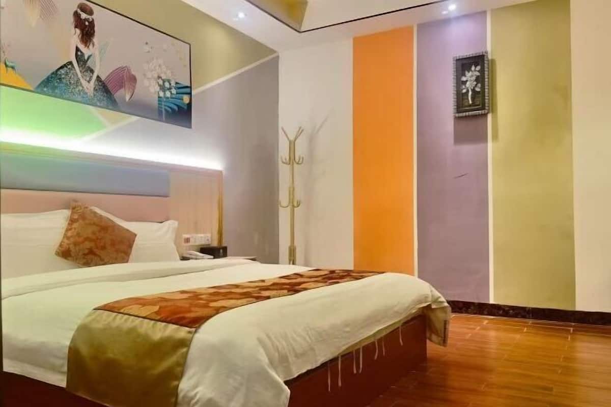 Habitación de hotel con una cama grande, cabecero, una obra de arte colgada en la pared, perchero y un cuadro enmarcado.