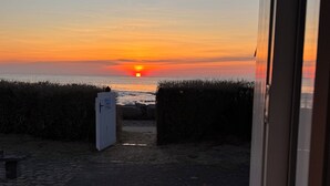 Un sentier menant à une plage, avec un coucher de soleil en arrière-plan.
