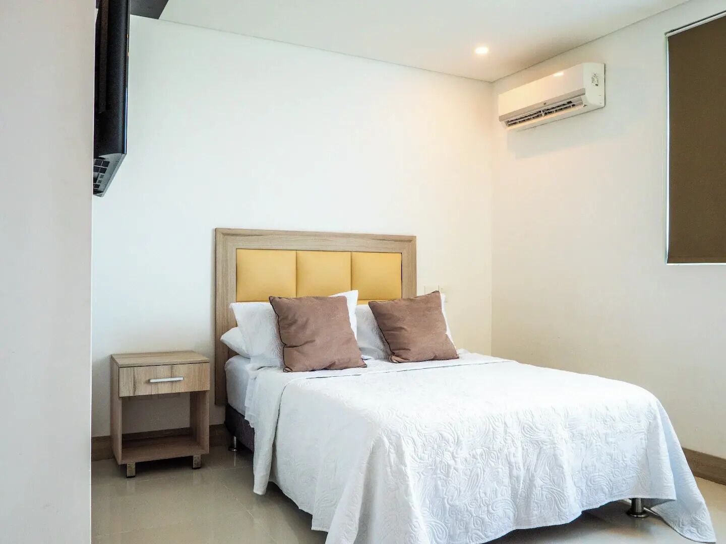 Une chambre à coucher avec un lit, une table de chevet et un appareil de climatisation fixé au mur.