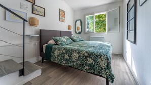 A bedroom with a bed, a staircase, a window, and wall-mounted artwork. - Le Martinet - Maison avec piscine (Robiac-Rochessadoule)