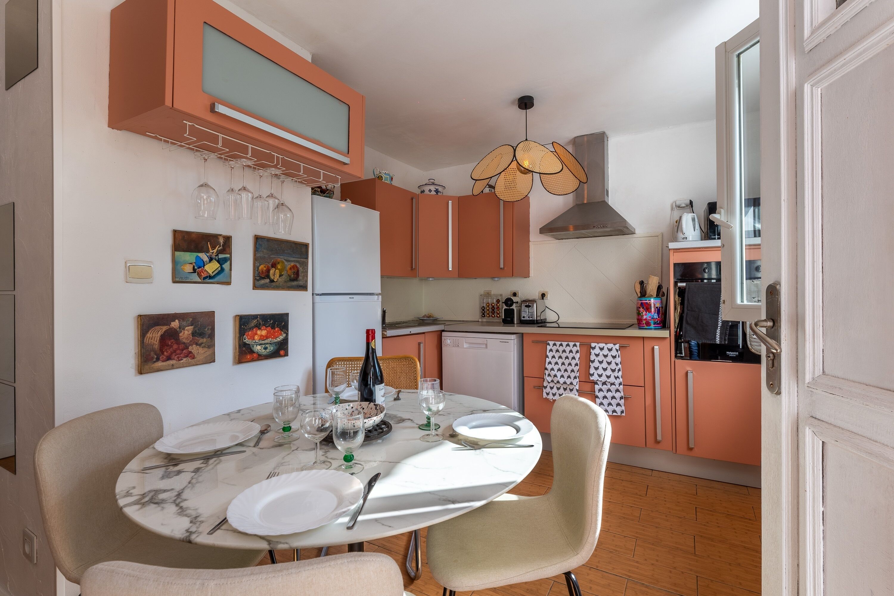 Une cuisine avec une table à manger dressée pour quatre personnes, équipée de verres à vin et d’une bouteille.