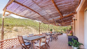 An outdoor patio with tables and chairs, a thatched roof, and a view of a hilly landscape. - Maison du Fangu - Da Simone - Maison de 160 m2 (Galéria)