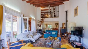 A spacious living room with a high ceiling, a staircase, a television, and a dining area. - Maison du Fangu - Da Simone - Maison de 160 m2 (Galéria)