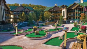 A resort with multiple-story buildings, a landscaped courtyard with green lawns and pathways, and a flagpole with an American flag. - Enjoy the Amazing Smoky Mountains!  (Sevierville)