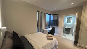 A modern hotel room with a bed, a desk, and a bathroom visible through an open door. - The Charm view London  (Londres)