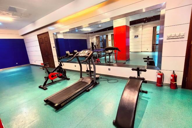 Ein Fitnessstudio mit Laufbändern, Crosstrainern und Langhantelbänken.