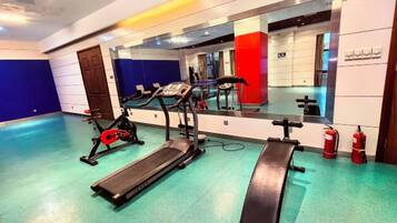 Ein Fitnessstudio mit Laufbändern, Crosstrainern und Langhantelbänken.