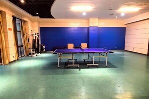 Une table de ping-pong se trouve dans une pièce dont un mur est bleu et où se trouve une porte sur le côté gauche.