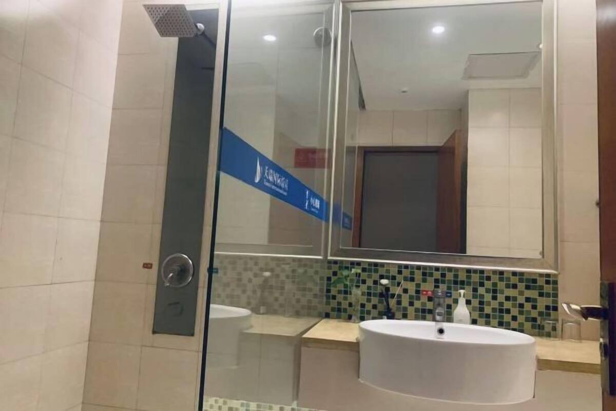 A modern bathroom with a glass shower enclosure, a large mirror, and a tiled backsplash.