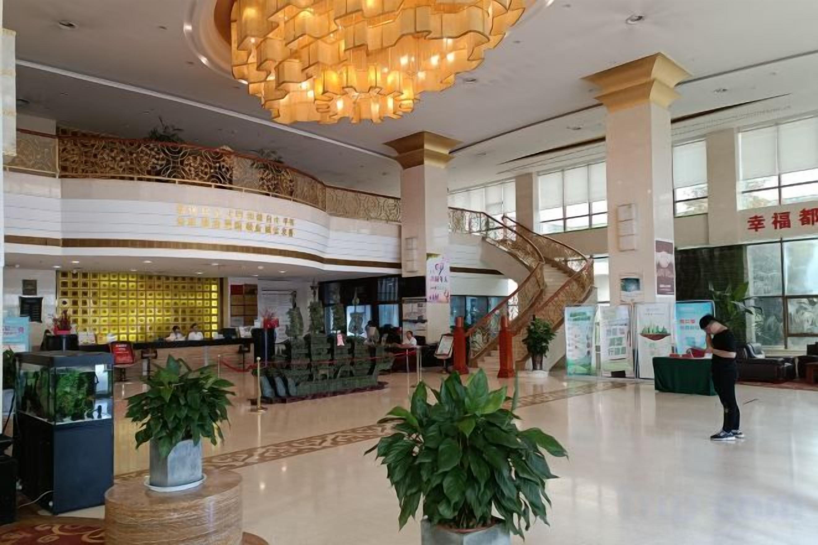 Eine Hotelhalle mit einer Rezeption, einer Treppe und einer großen Kronleuchter.