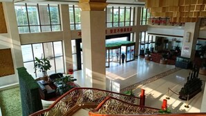 A spacious lobby with a high ceiling, large windows, and a central staircase. - Tianrui Zhongzhou International Hotel (Ruzhou)