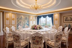 Un comedor formal con una mesa redonda, sillas estampadas con motivos florales y una araña.