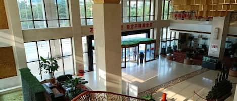 A spacious lobby with a staircase, large windows, and a reception area.