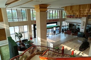 Un hall espacioso con una escalera, ventanas grandes y una zona de recepción.