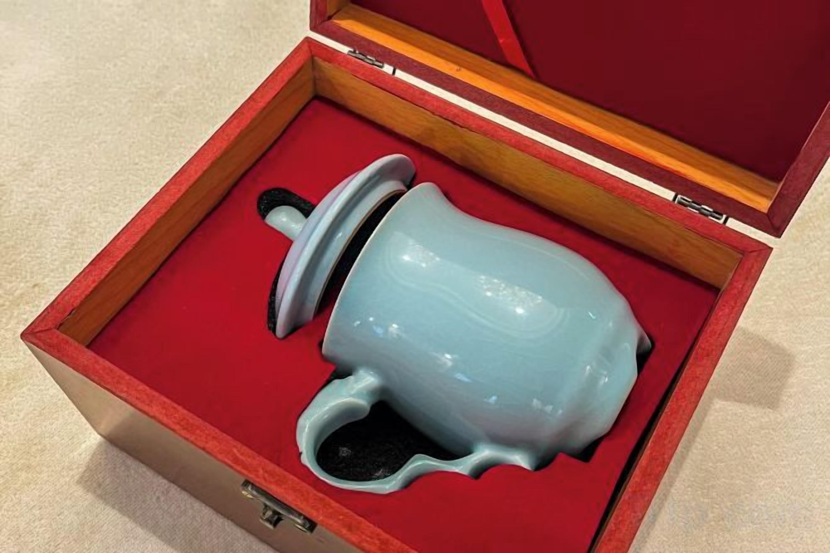A ceramic object in a red-lined box with a wooden interior.