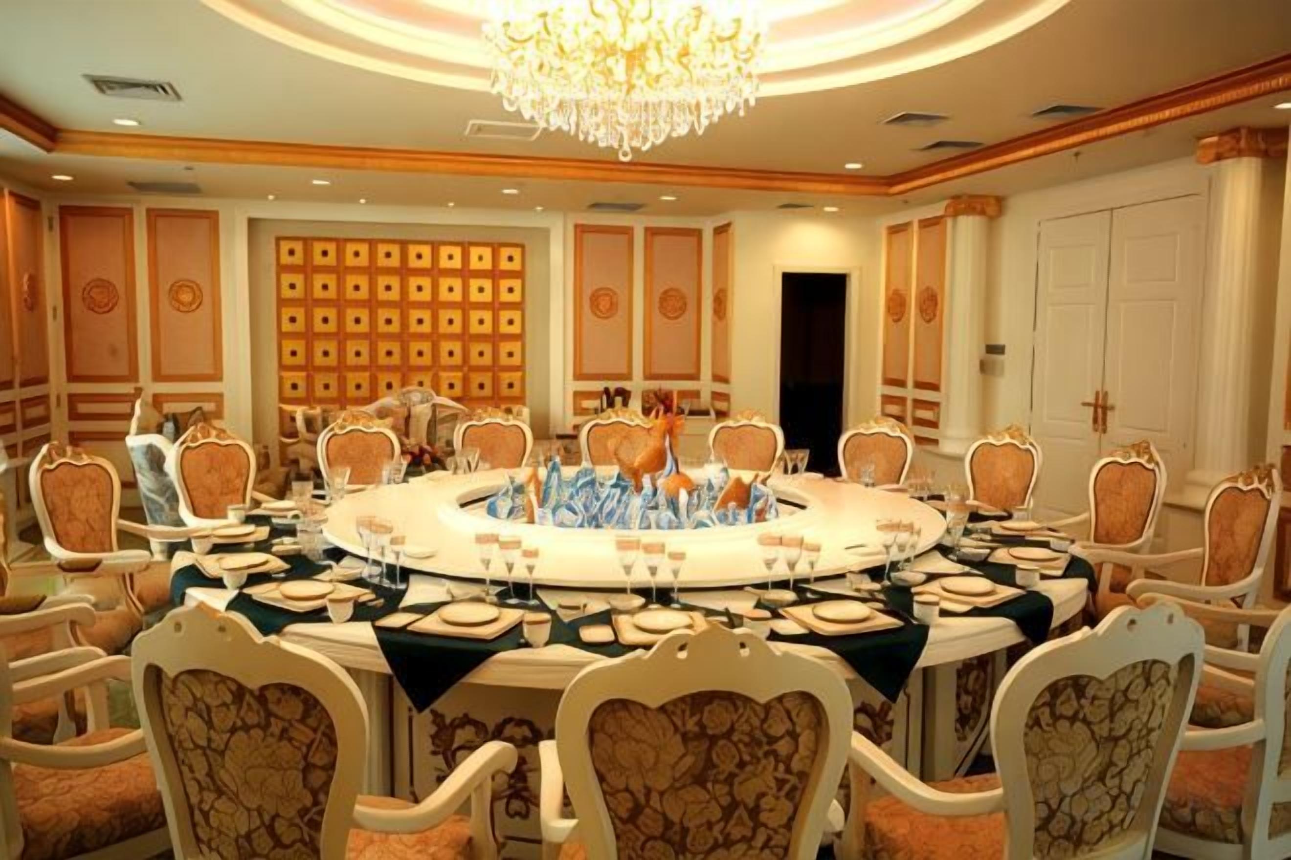 A conference room with a round table, chairs, and a chandelier.