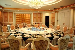 Une salle de conférence avec une table ronde, des chaises et un lustre.