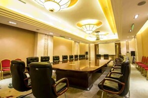 Un salón de conferencias con una larga mesa y sillas, equipado con un proyector y una pantalla.