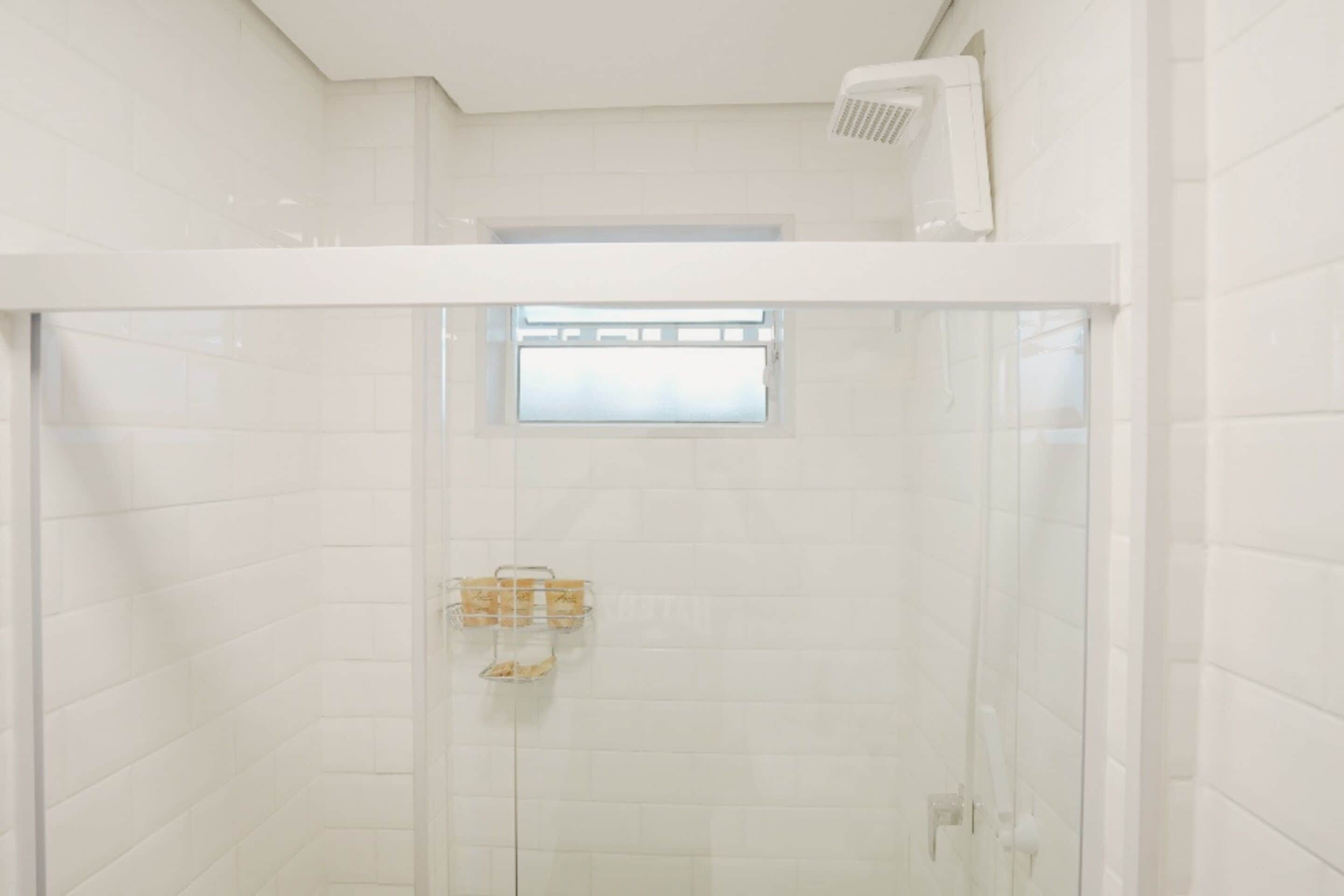 Una ducha moderna con puerta de vidrio, una ventana pequeña y un perchero para toallas.