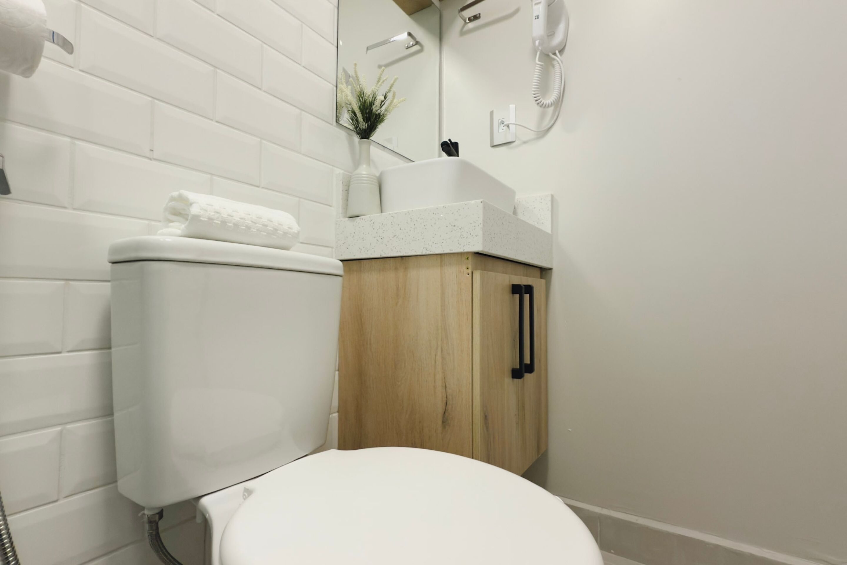 A bathroom with a white toilet, a wooden cabinet, a white sink, and a mirror.